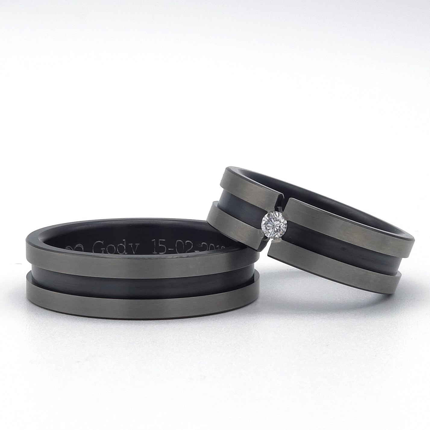 Twee zirkoniumringen met matte grijze randen; één ring met een briljant van 0.07ct in spanningszetting