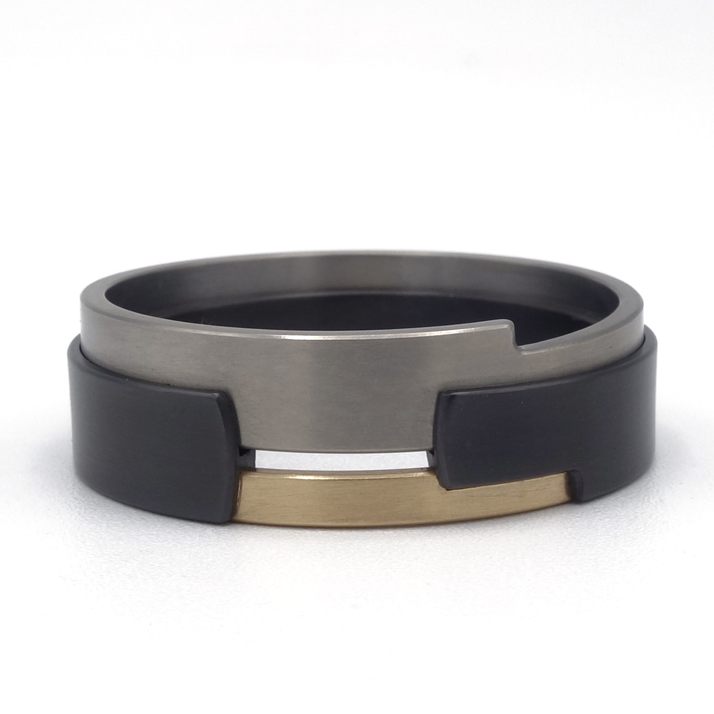 Aquila Black-ring van zirkonium, titanium en geelgoud – moderne ring met grafisch lijnenspel en sterk kleurcontrast.