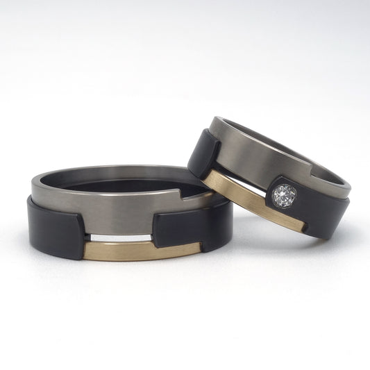 Aquila Black ringenset van zwart zirkonium, titanium en geelgoud – grafisch lijnenspel met diamantaccent in de damesring.