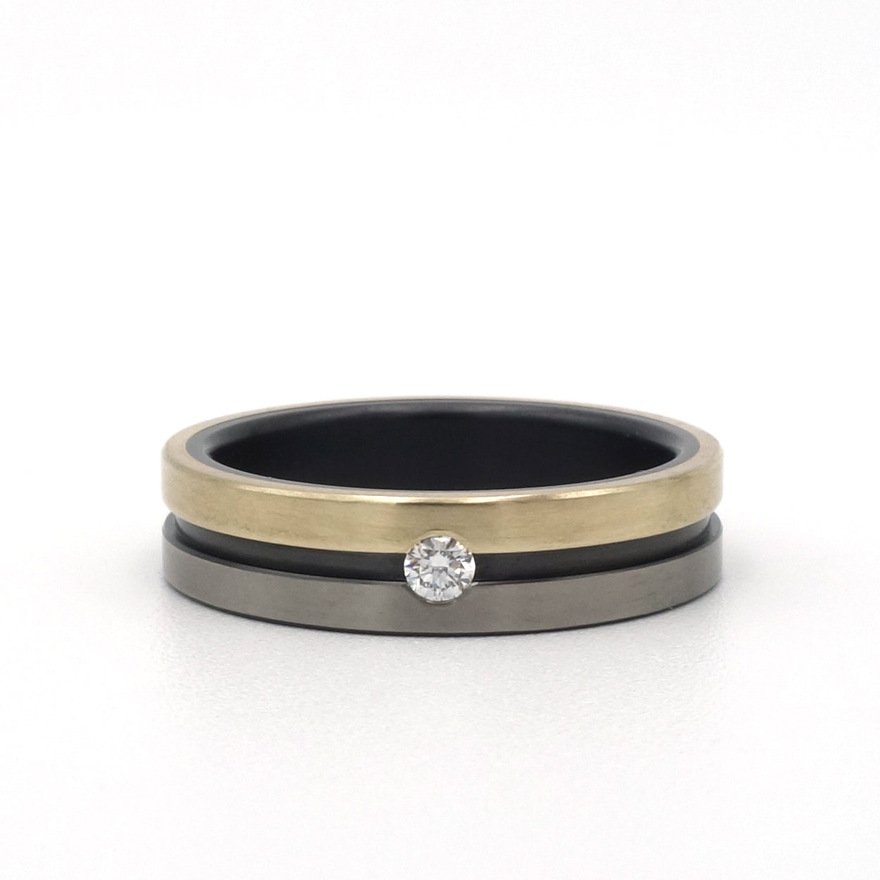 Lines-ring van zwart en blank zirkonium met 14kr geelgoud en een 0.05ct diamant in optische spanzetting.