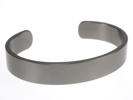 Brede matte titanium armband in open design, liggend op een witte achtergrond.