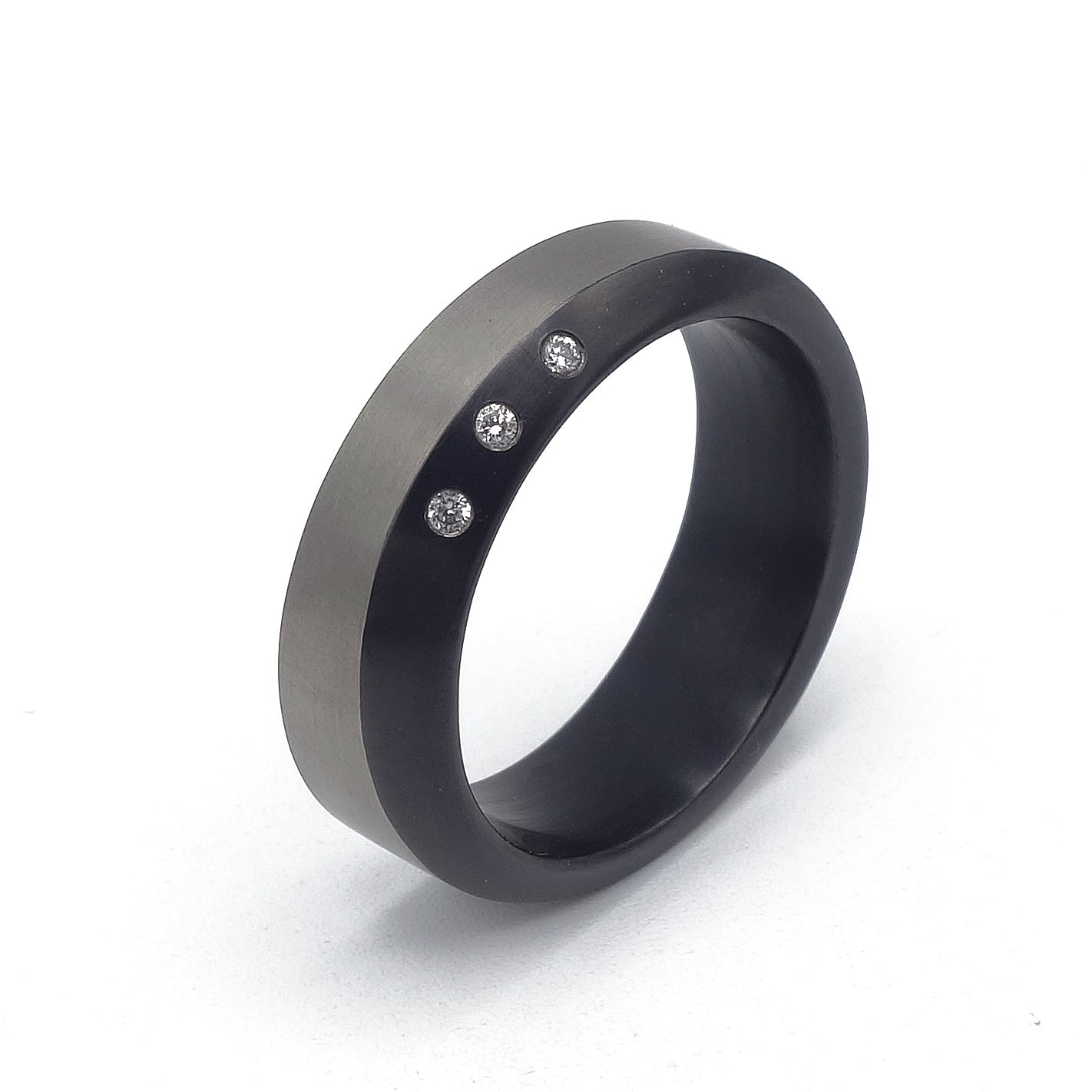 Zirkonium ring met drie kleine diamanten en een golvend profiel, moderne afwerking.