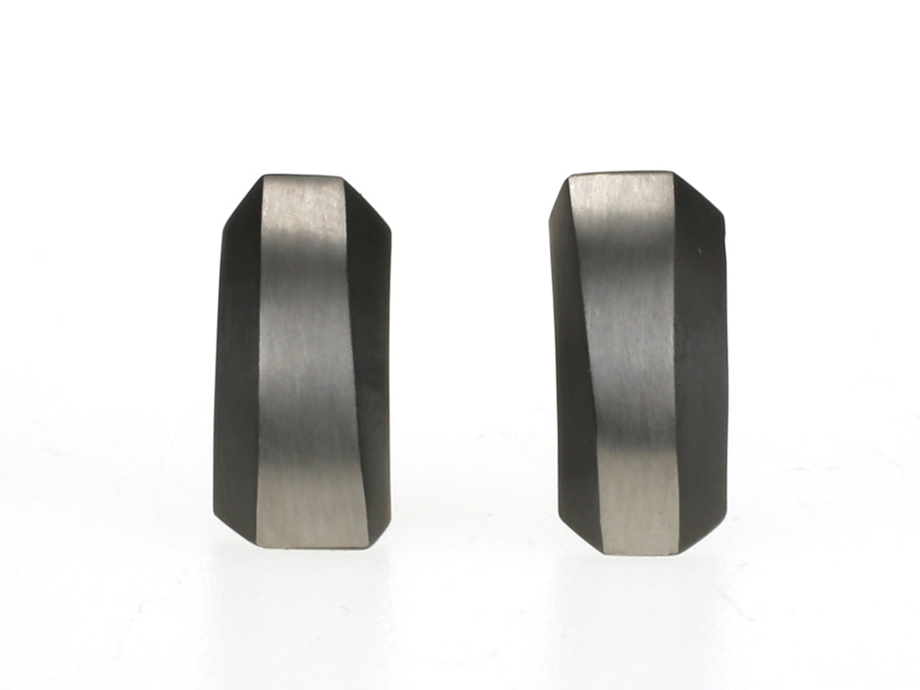 Rechthoekige oorbellen van zwart zirkonium met grijze matte strook en golvende facetten.