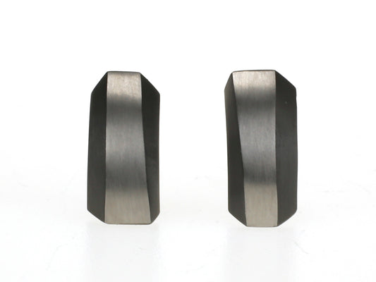 Rechthoekige oorbellen van zwart zirkonium met grijze matte strook en golvende facetten.