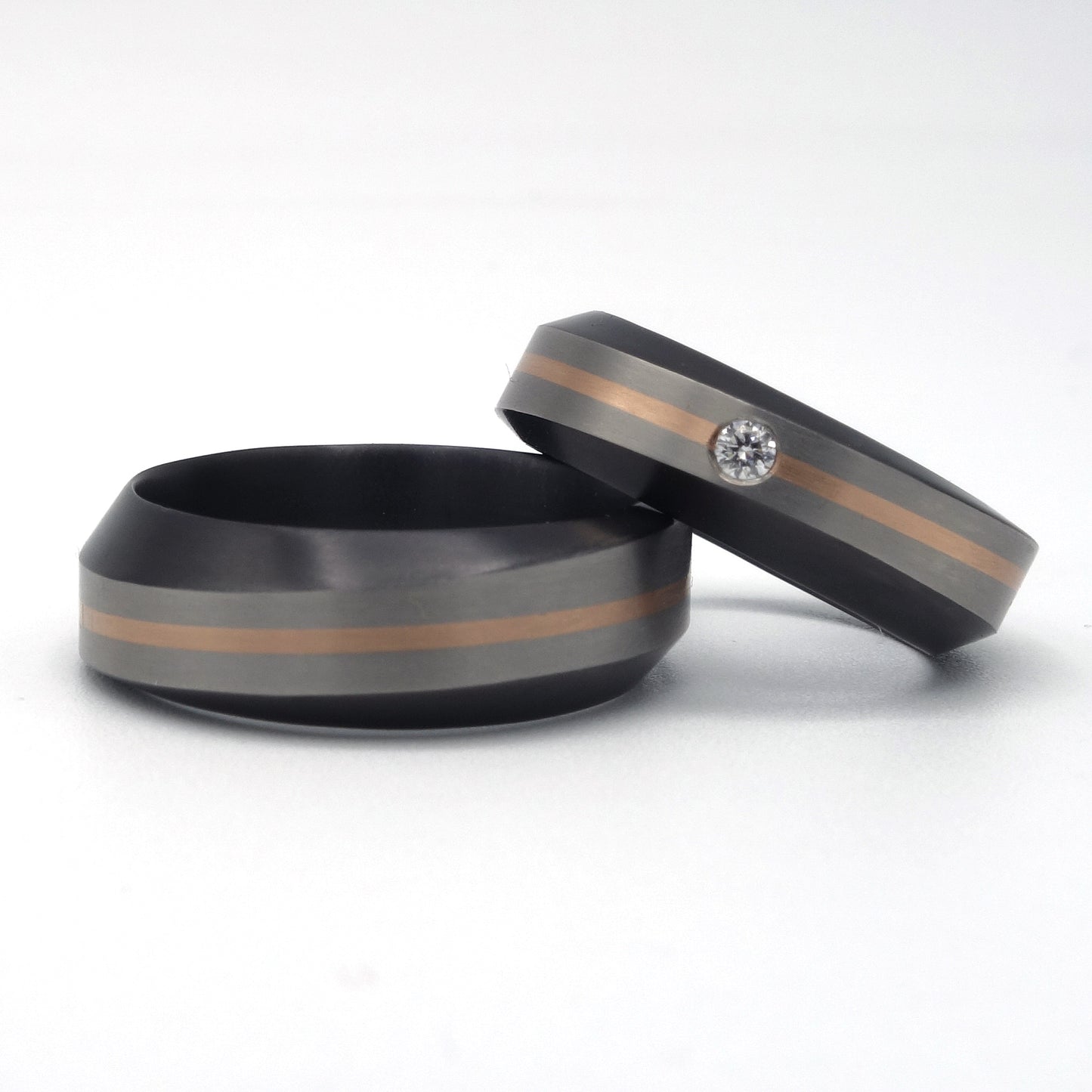 Set zirkonium trouwringen met grijze band en 0,8 mm roodgouden inleg; één ring met diamant, één zonder.