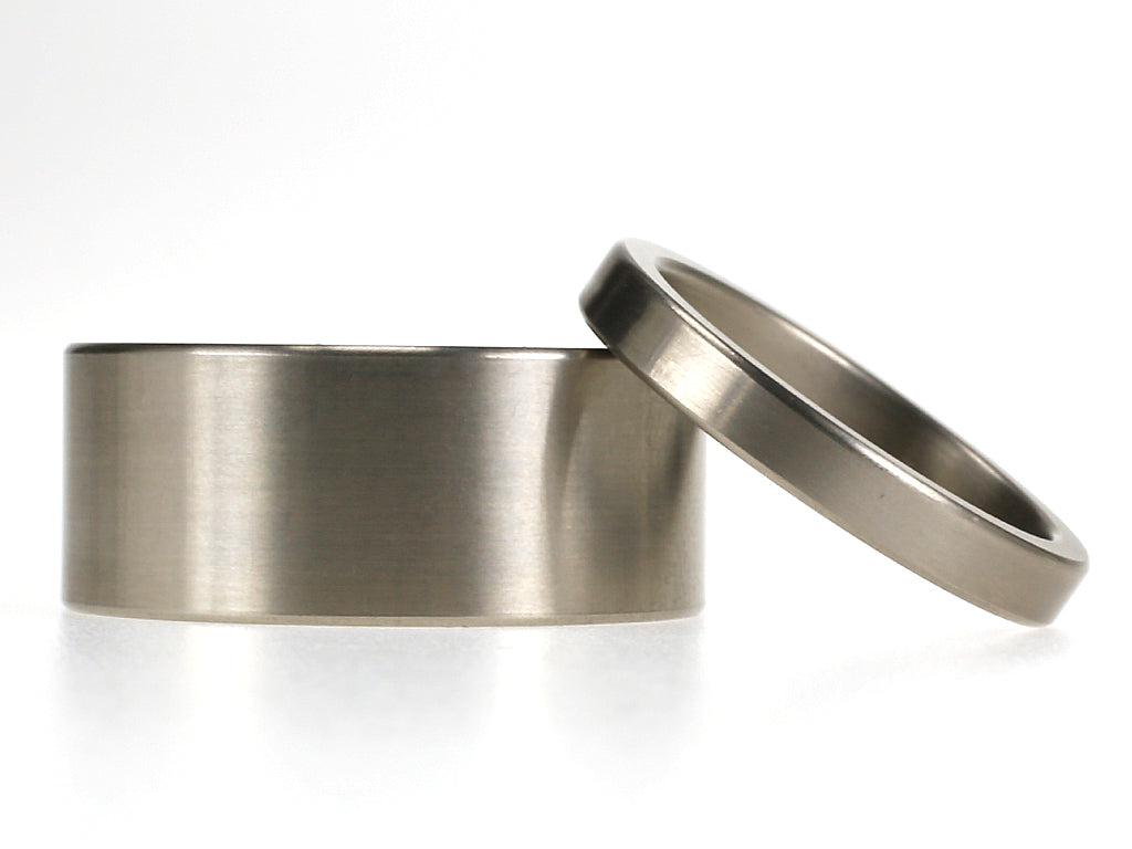 Titanium trouwringenset met brede 9 mm herenring en smalle 3 mm damesring, beide met matte afwerking.