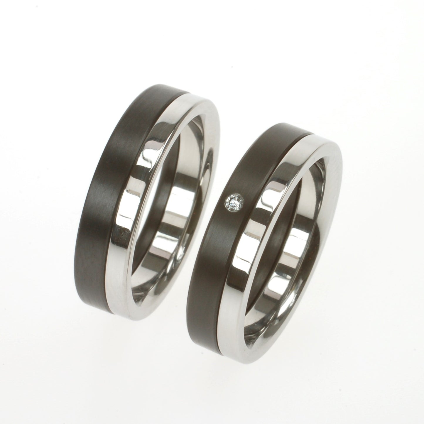 Twee ringen van zirkonium en edelstaal; één met kleine diamant van 0.02ct in verzonken zetting