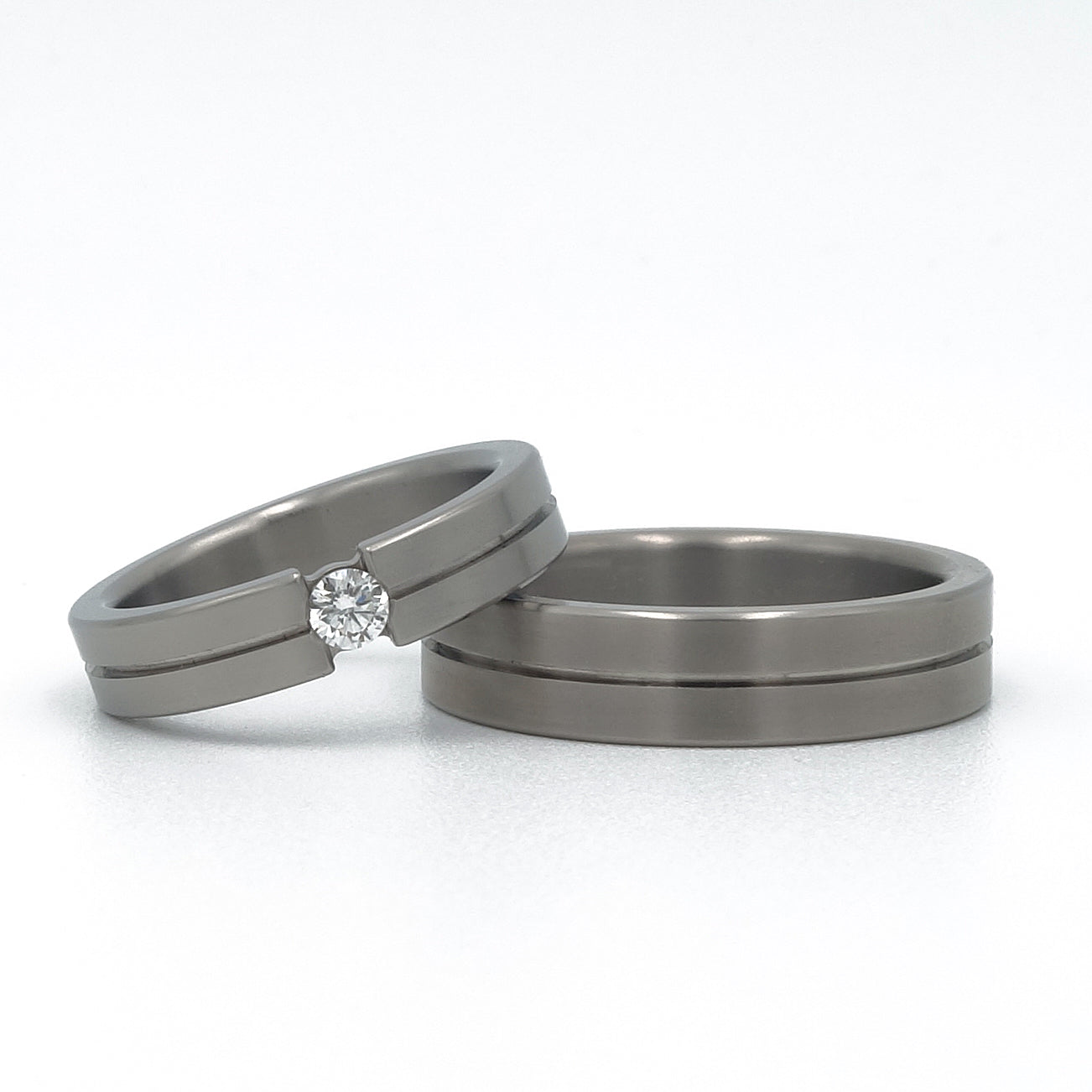 Titanium trouwringen Grey Stripe met grijze lijn en damesring met 0.10ct diamant in optische spanzetting.