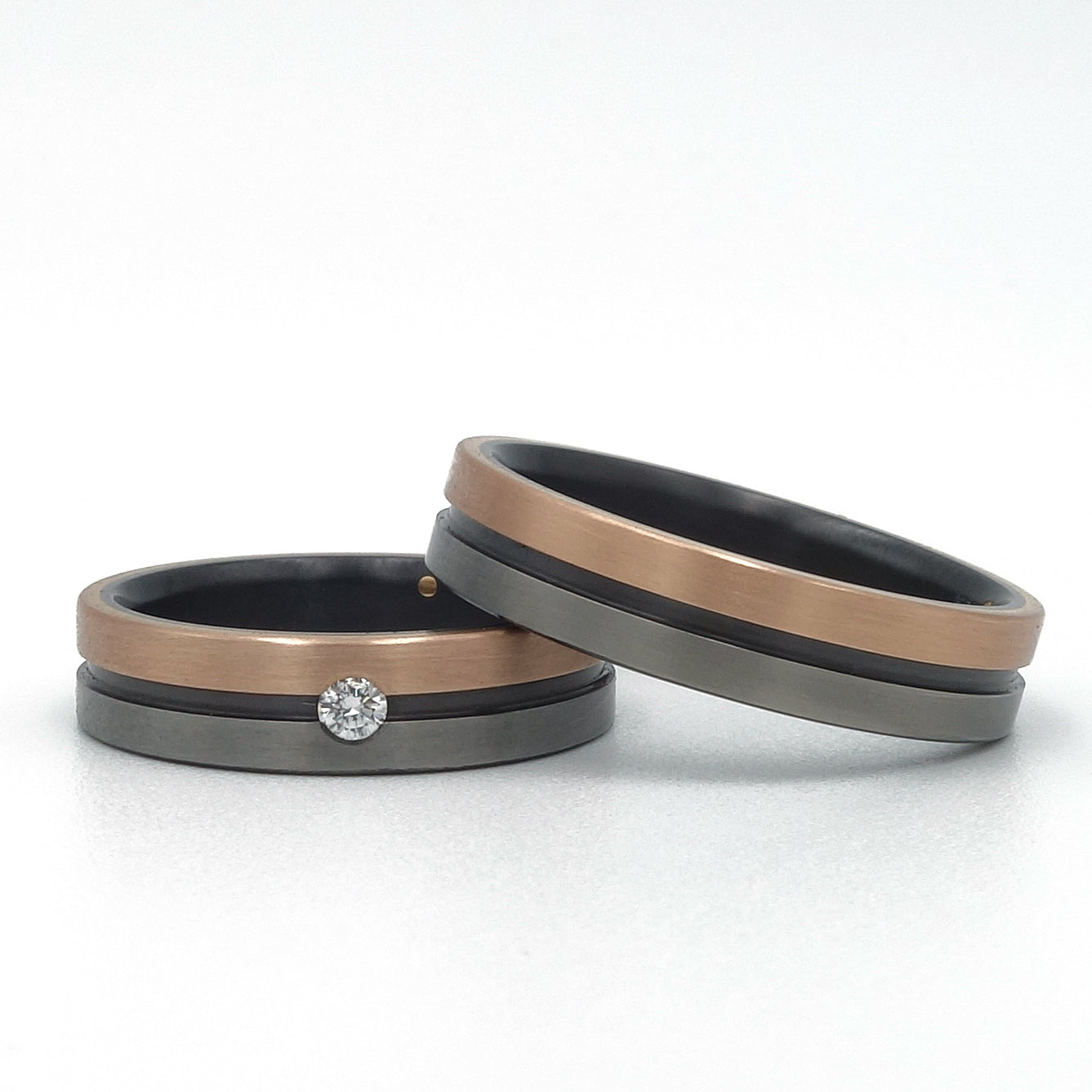 Lines ringenset van zirkonium en 18k roodgoud – moderne trouwringen met strak lijnenspel en warm roodgouden detail.