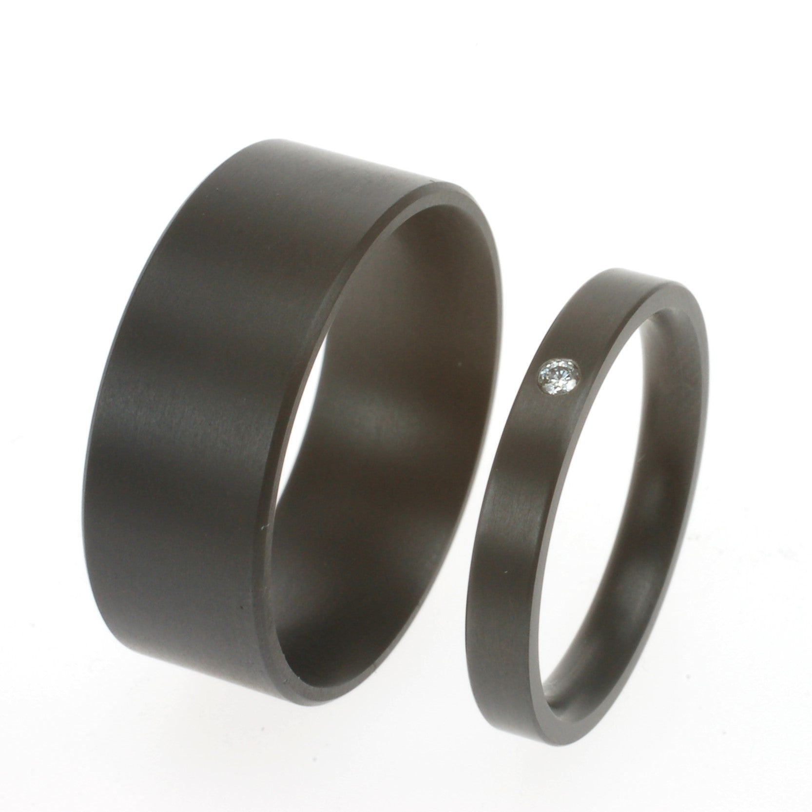 Zwarte zirkoniumringen; één smalle ring met diamant van 0.01ct en één brede ring zonder steen