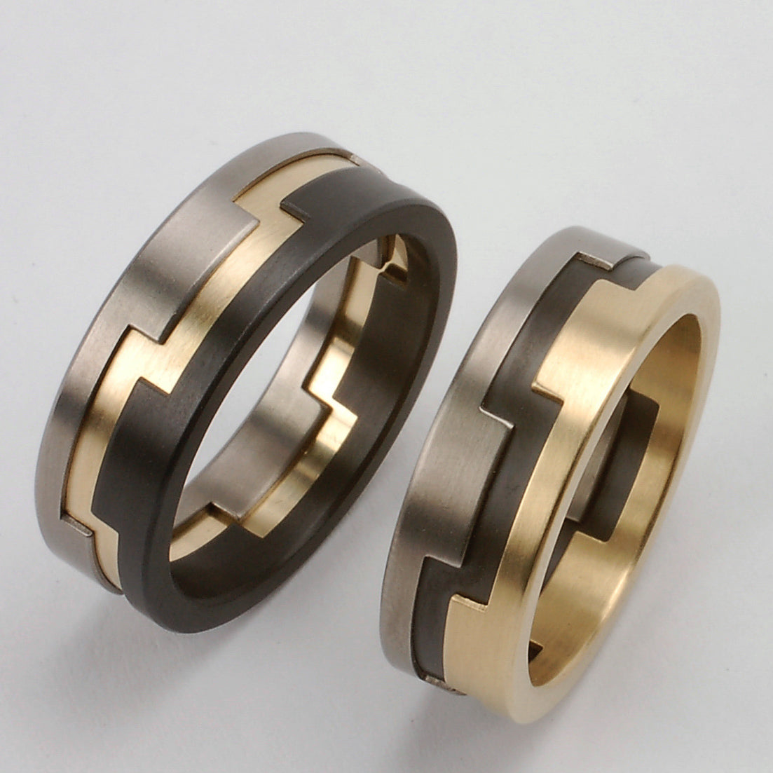Trouwringenset met in elkaar grijpende segmenten van geelgoud, titanium en zwart zirkonium
