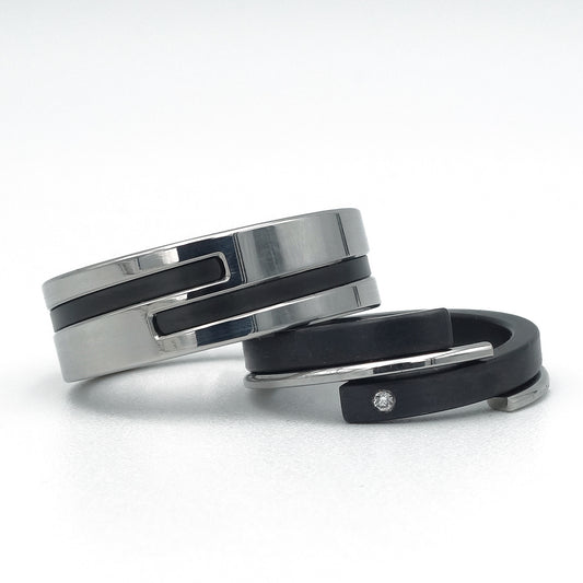 Moderne trouwringen: brede edelstalen ring met zwarte inleg (zirkonium) en smalle zwarte ring (zirkonium) met stalen zijring en diamant – Adam & Eva in staal en zwart.