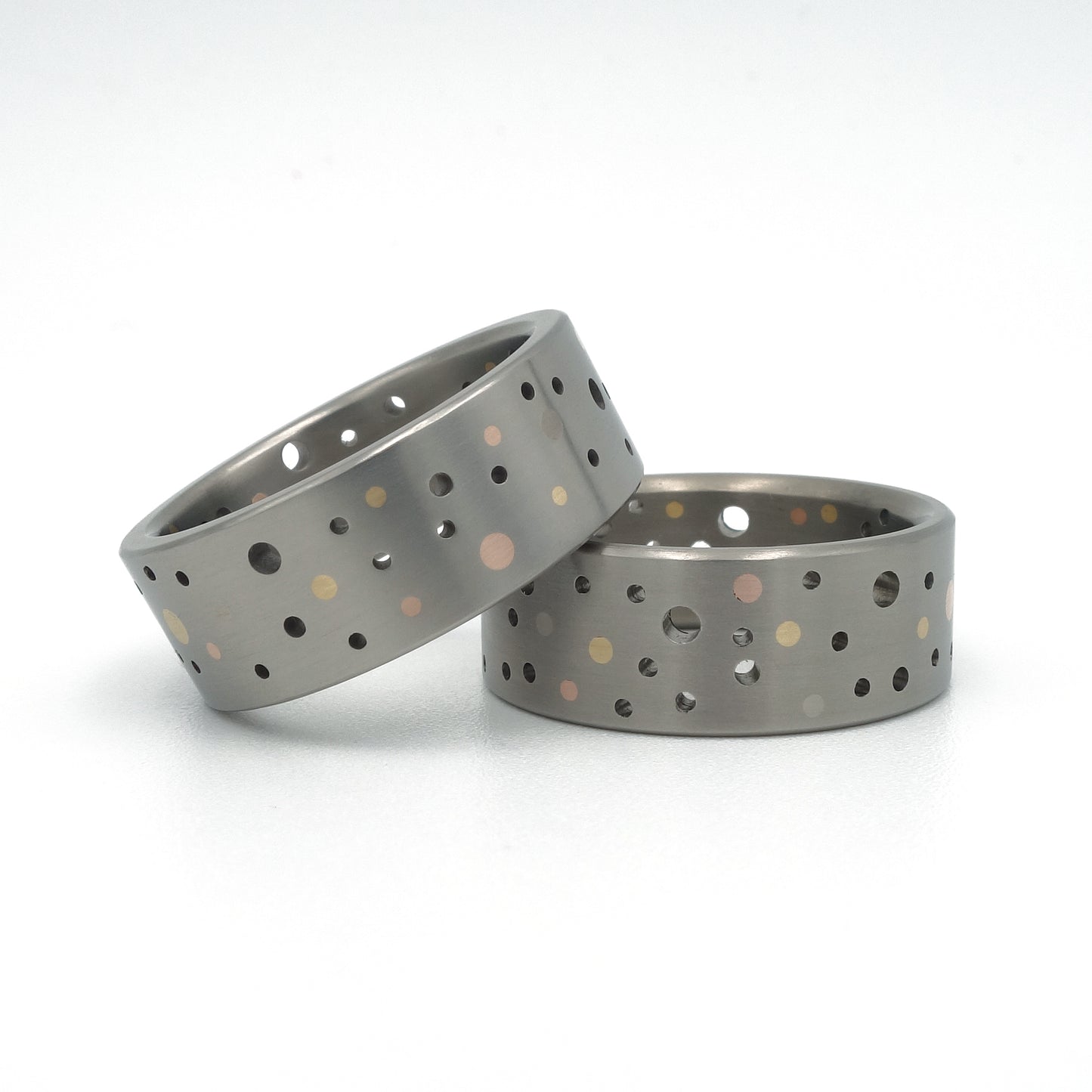 Set titanium Confetti-ringen met gouden en platina stippen in willekeurig gatenpatroon.