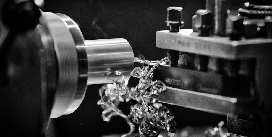 Draaibank met metaalspanen in actie – zwart-witfoto van het productieproces van metalen sieraden.