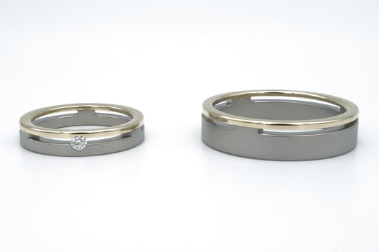 Brede titanium trouwringen met gele gouden rand. Damesring met 0.05ct diamant, robuuste herenring.