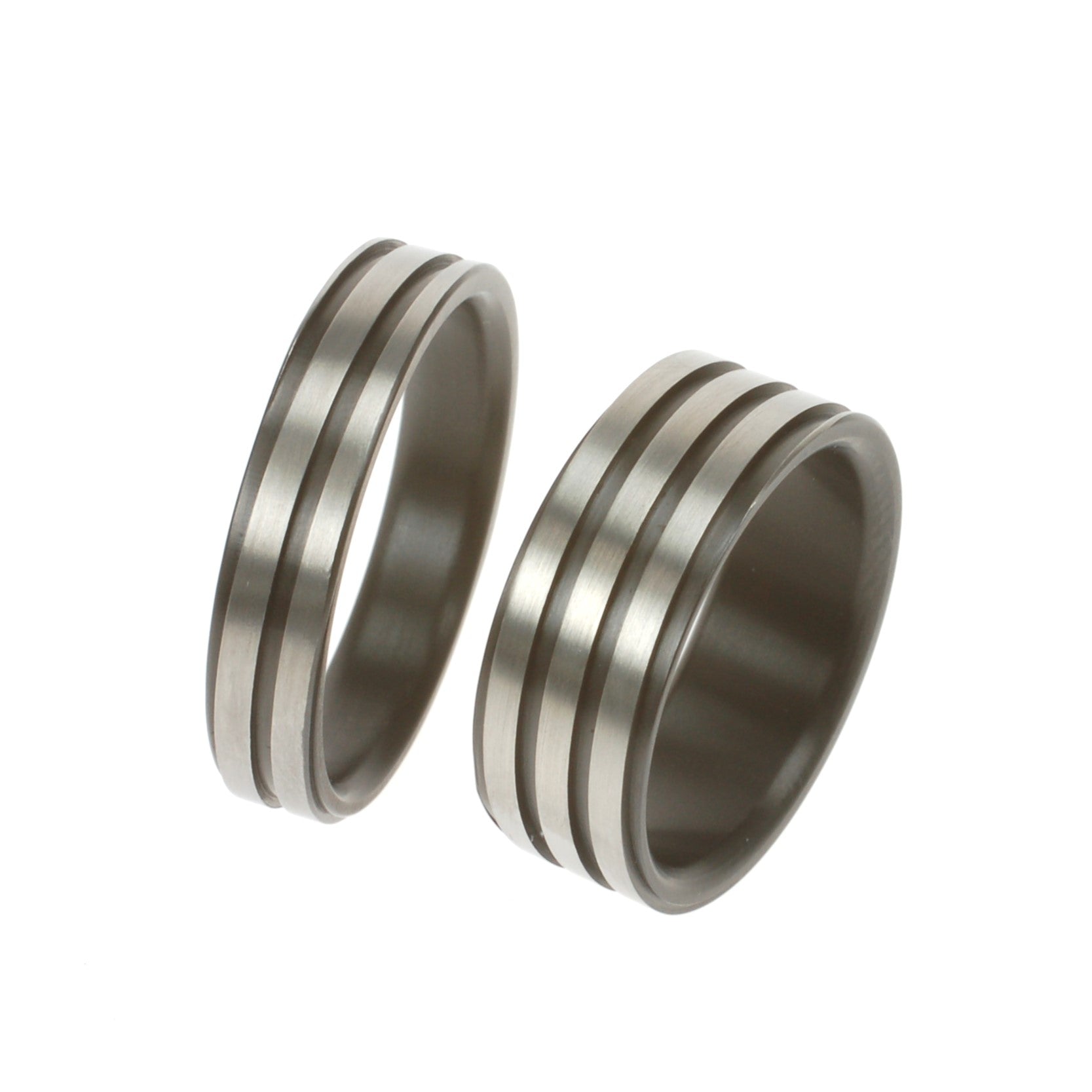 Twee zirkoniumringen met symmetrische groeven; één van 5 mm met twee groeven, één van 8 mm met drie groeven, mat afgewerkt.
