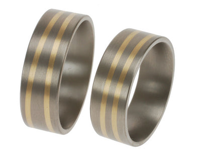 Titanium trouwringen met twee schuine lijnen van 18kr geelgoud die langs elkaar bewegen.