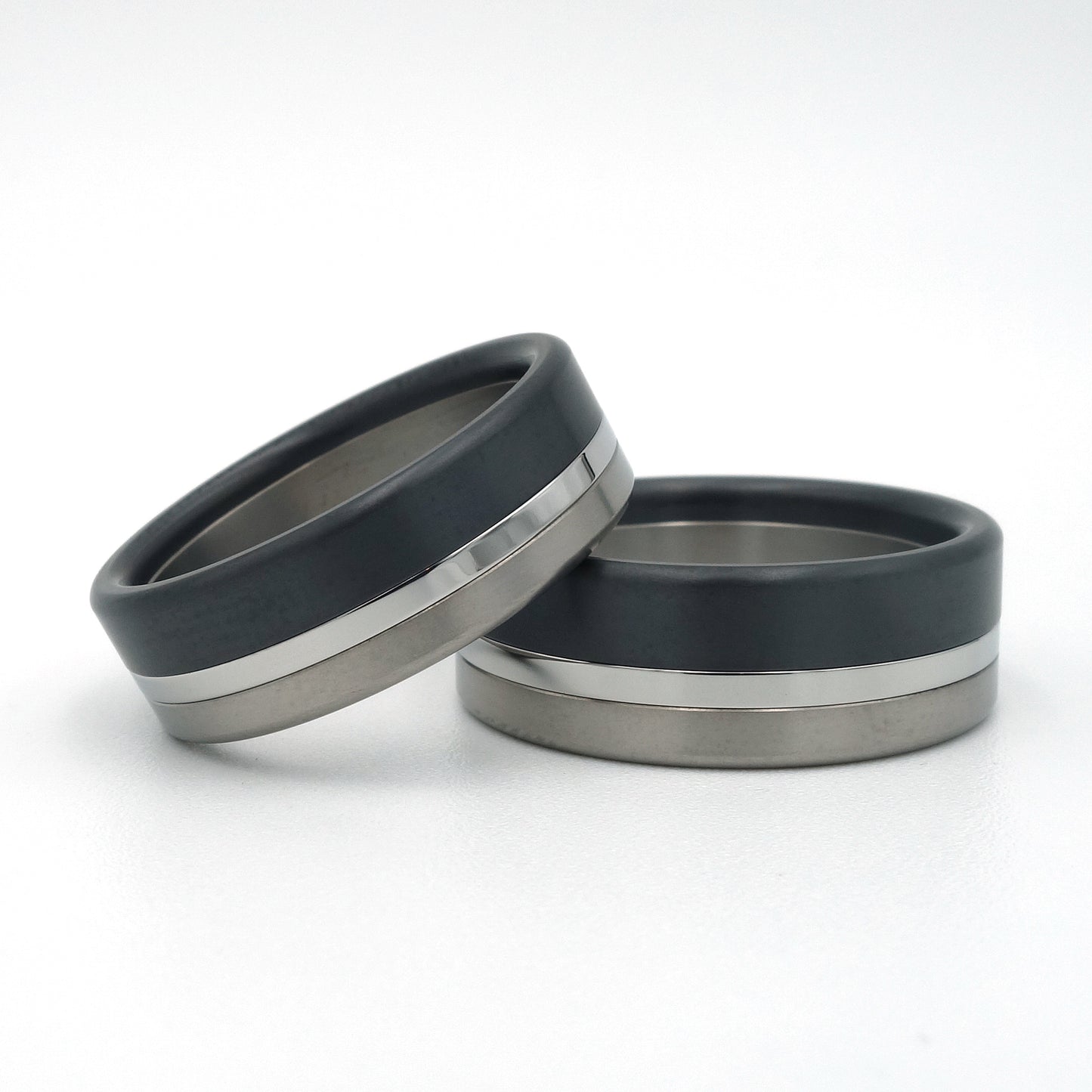 Noir Bond ringenset van titanium, zirkonium en edelstaal – stoer, technisch ontwerp met contrasterende lagen en industriële uitstraling.