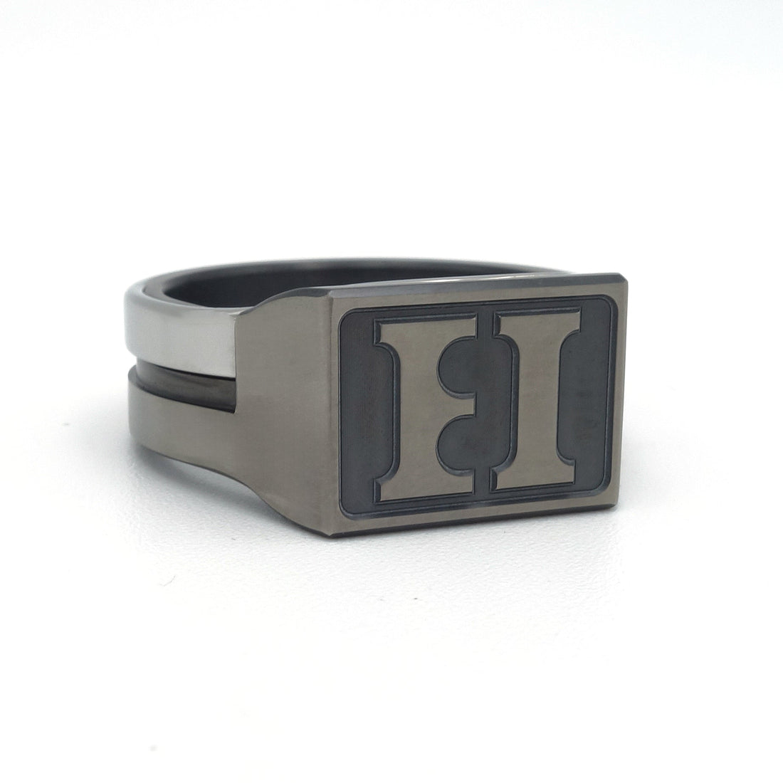 Moderne zegelring in grijs en zwart zirkonium met edelstalen band. Rechthoekige zegelplaat met verdiept gefreesd initialen, geschikt als stempel in zegellak.