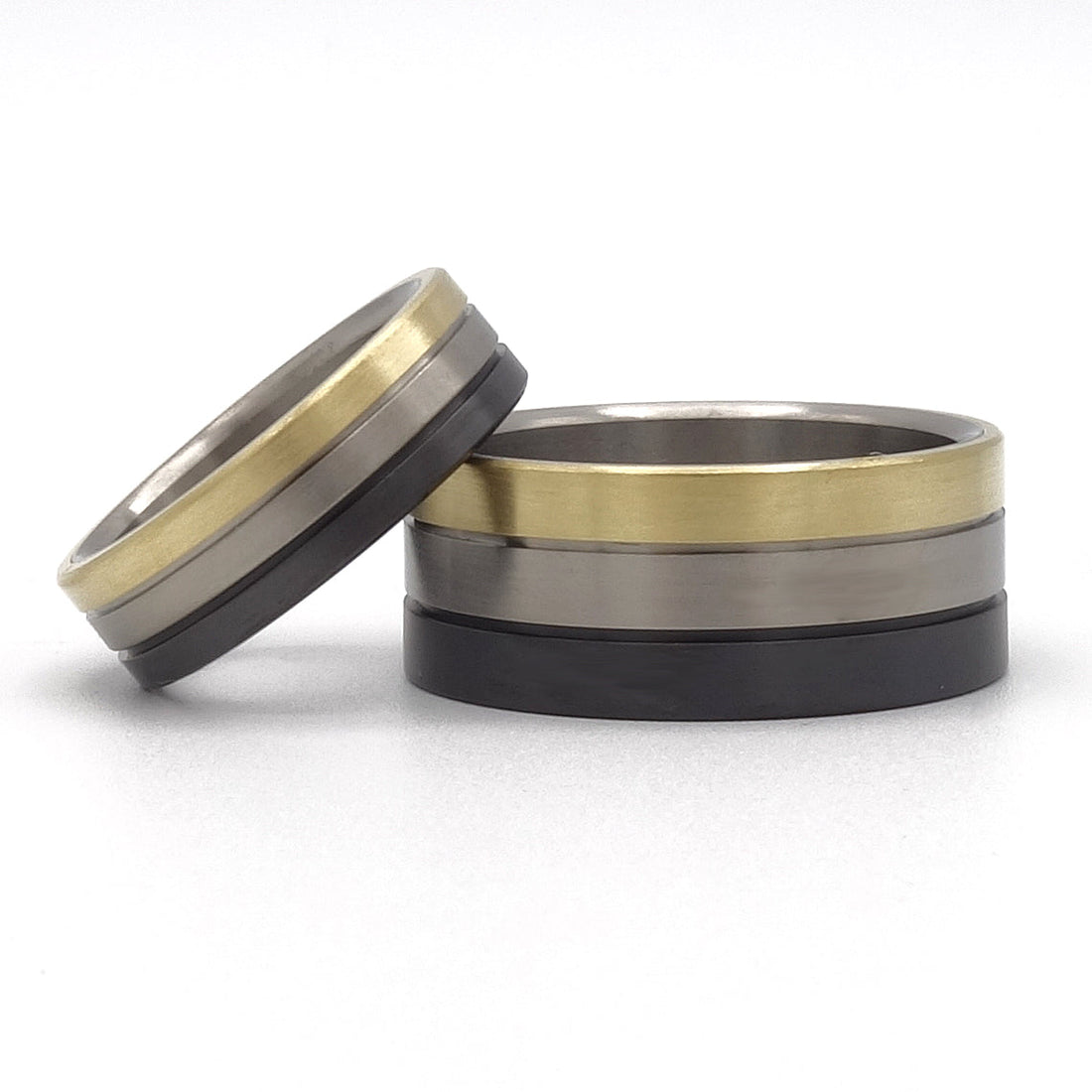Anke trouwringen set van zwart zirkonium, titanium en 18kr geelgoud – brede herenring en smalle damesring