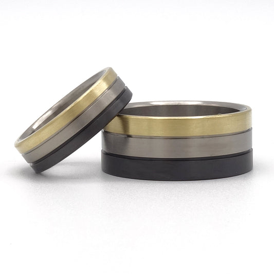 Anke trouwringen set van zwart zirkonium, titanium en 18kr geelgoud – brede herenring en smalle damesring