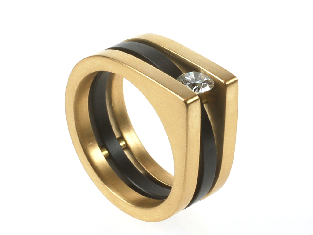 Typiche gouden Metal art ring met zwart zirkonium aan de binnenkant en een diamant die uit het midden hangt tussen  de 2 gouden ringen