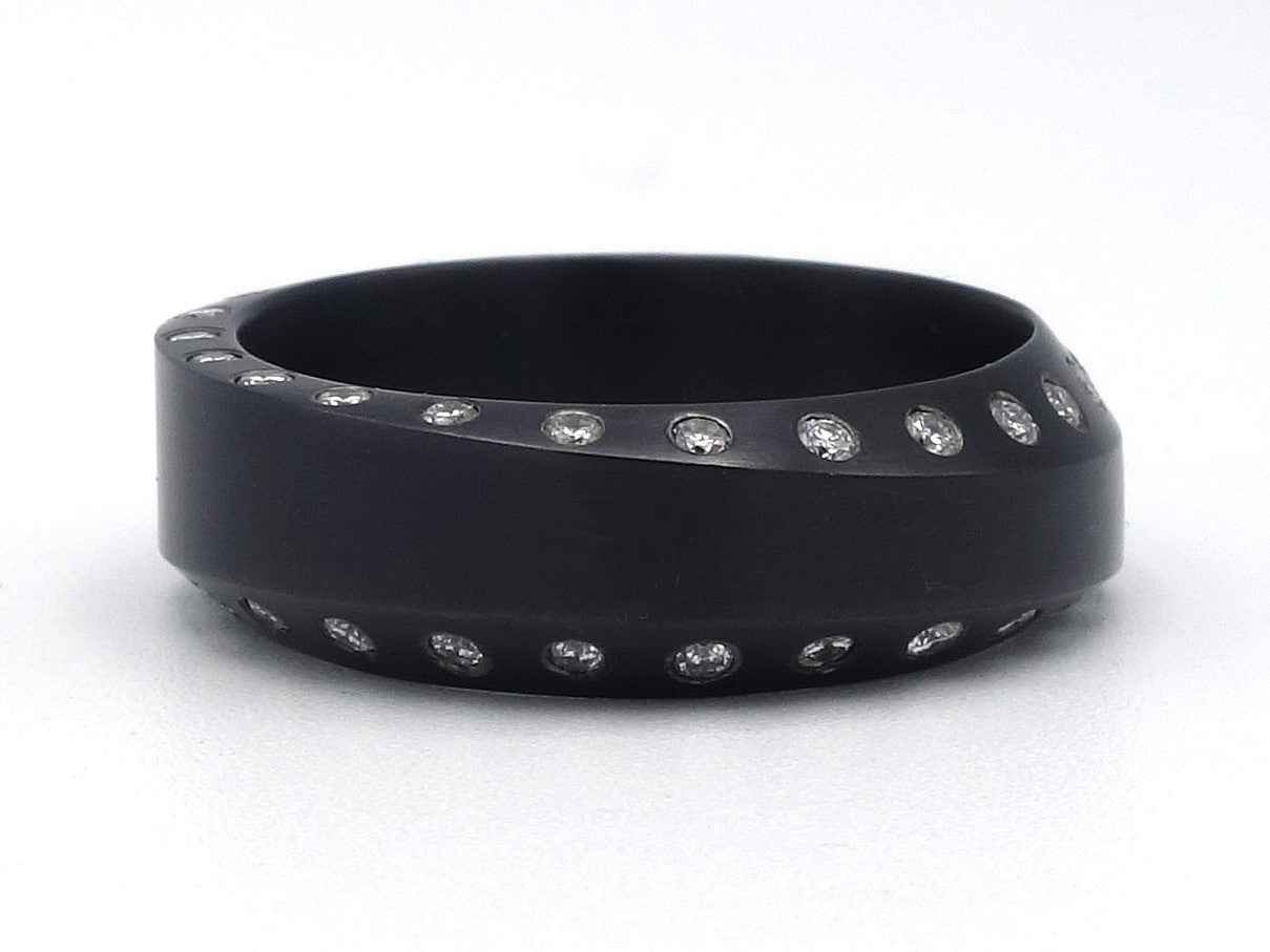 Zwarte ring met schuine randen en rond om witte diamanten gezet