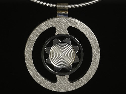 Exslusieve hanger met zwarte achtergrond. Van een titanium bloem omarmd door meer titanium en zirkonium