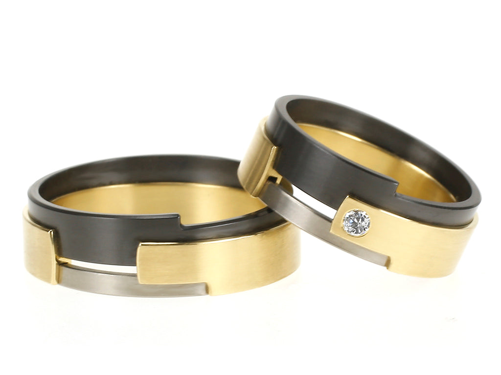 Aquila trouwringen van geelgoud en palladium met zwart zirkonium, één ring gezet met diamant.