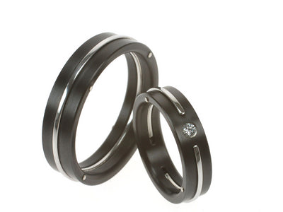 Zwarte trouwringen van zirkonium met strakke dubbele groef, één ring gezet met diamant.