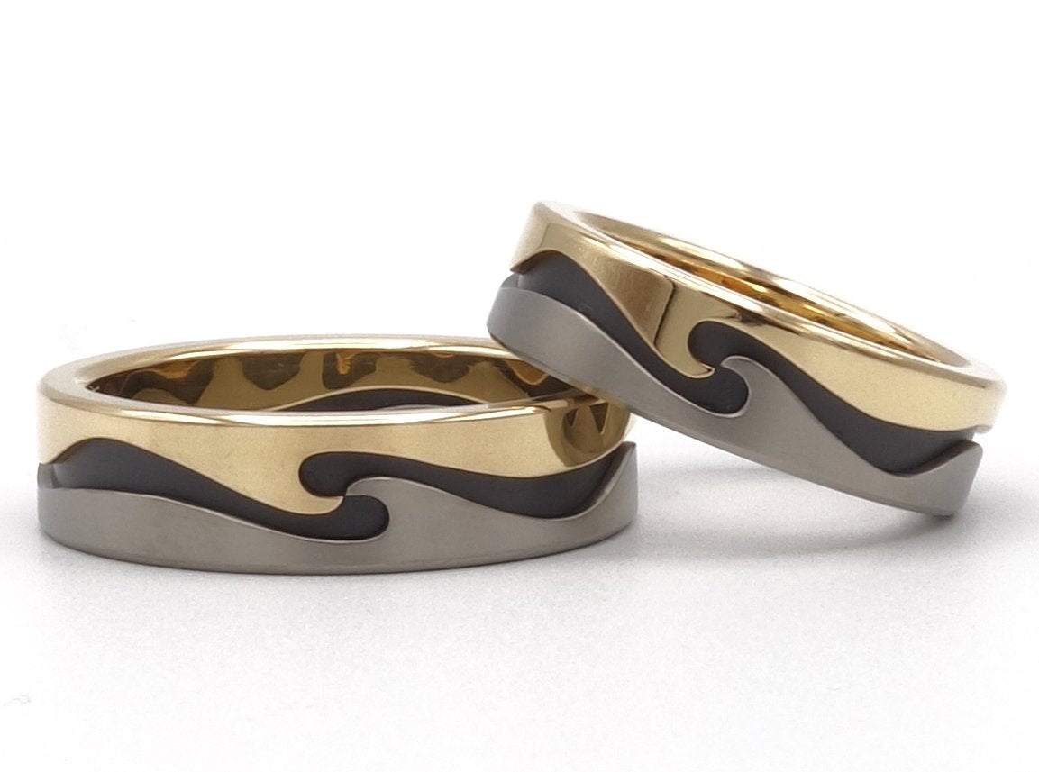 Speciale trouwringen van geelgoud, titanium en zwart zirkonium met golvend design.