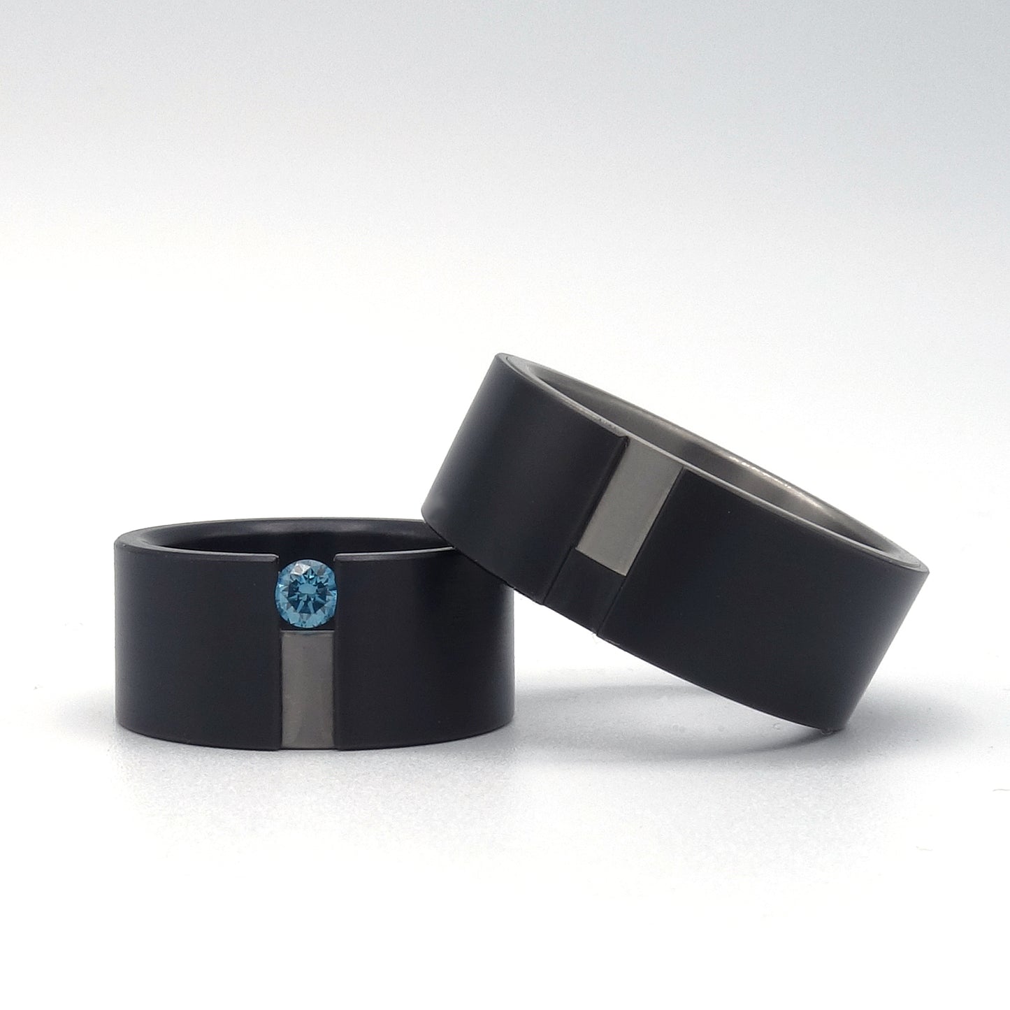 Set trouwringen Sora in zwart zirkonium met titanium zij-insteek, damesring gezet met een sky blue diamant van 0.15ct.