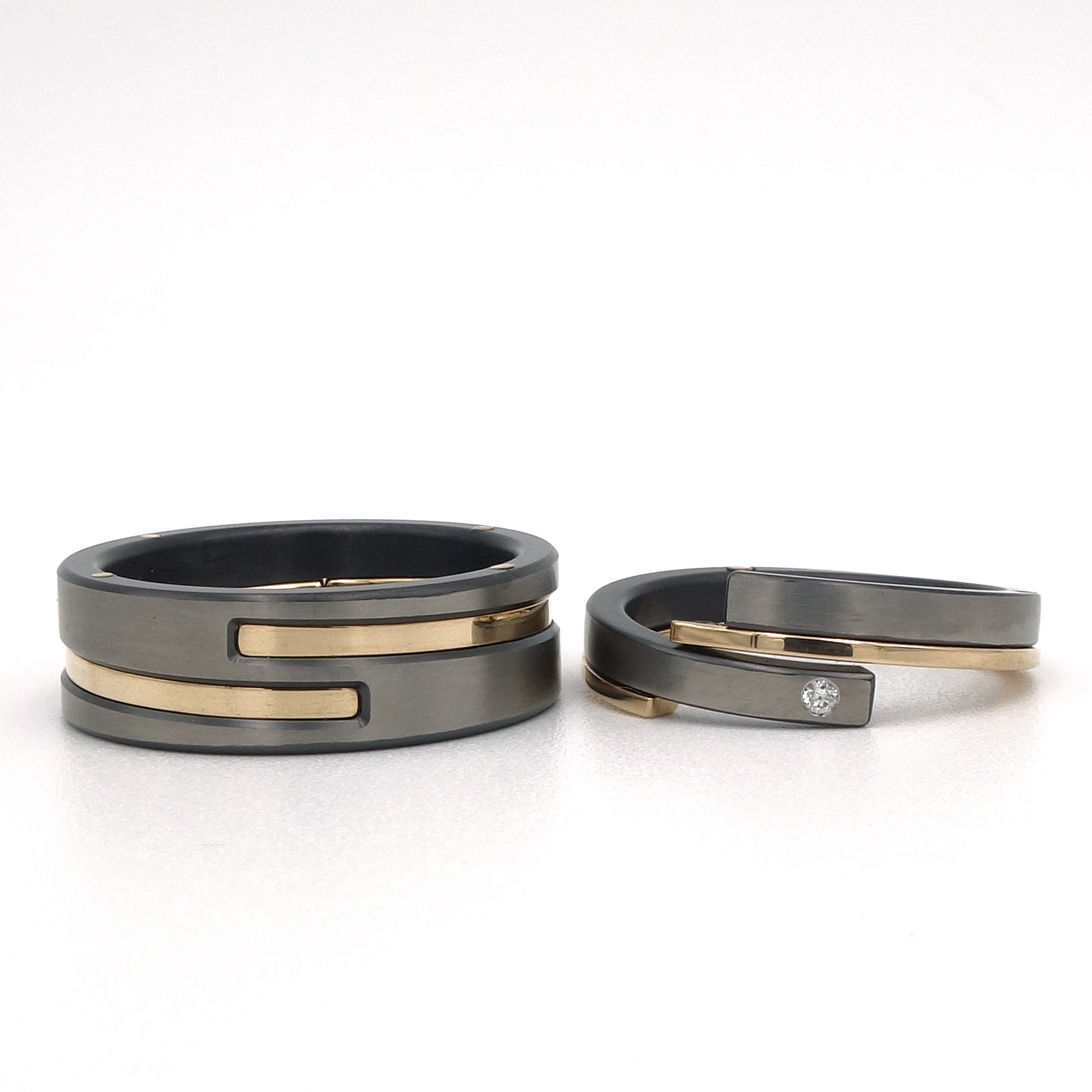 Mat grijs-zwarte zirkonium trouwringenset met glanzende 14kr geelgouden accenten en diamant van 0,015 ct in de damesring.