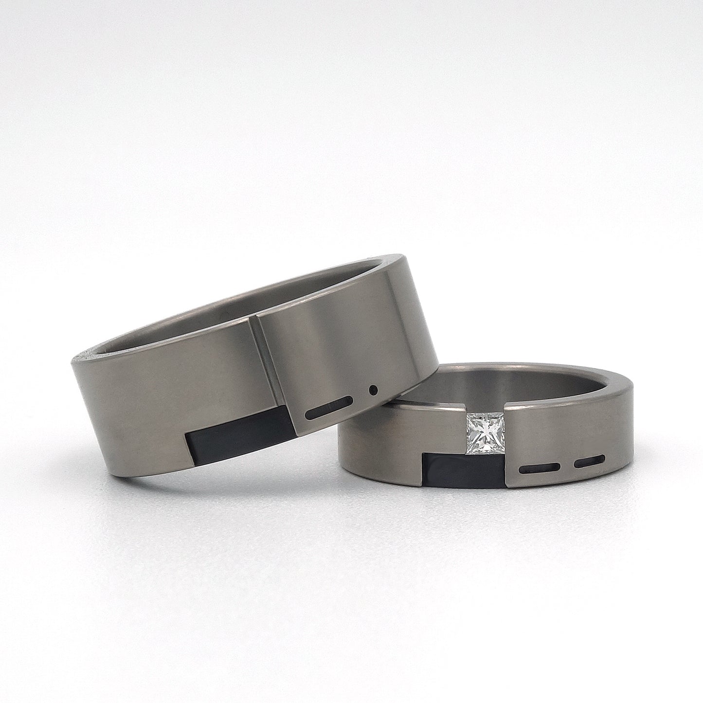 Set trouwringen Leona & Leon in titanium met zwart zirkonium, met de voorletter van de partner verwerkt in morsecode; Leona gezet met een prinsesgeslepen diamant van 0.15ct.