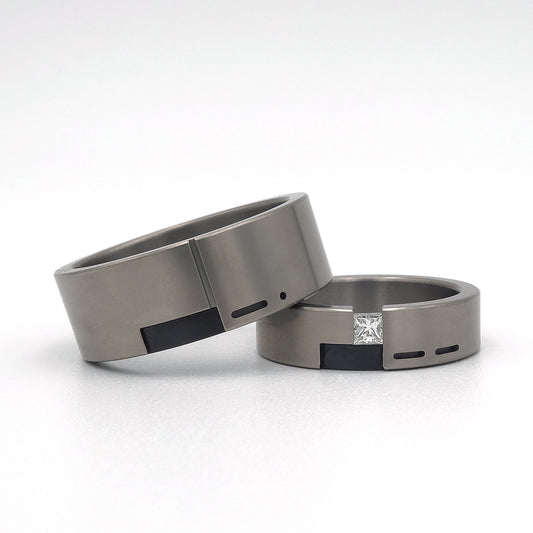 Set trouwringen Leona & Leon in titanium met zwart zirkonium, met de voorletter van de partner verwerkt in morsecode; Leona gezet met een prinsesgeslepen diamant van 0.15ct.