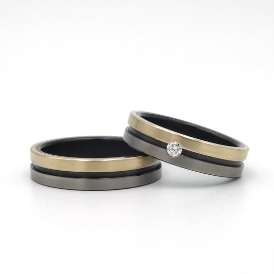 Lines-ringen van zwart en blank zirkonium met 14kr geelgoud, waarvan één met een 0.05ct diamant in optische spanzetting.