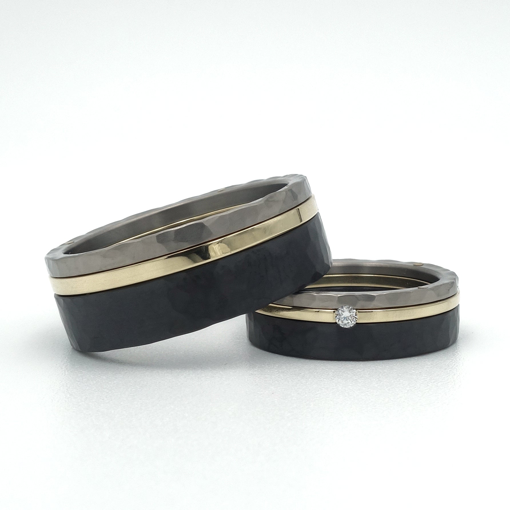 Set trouwringen met titanium, zwart zirkonium en 14kr geelgoud, hamerslagstructuur, damesring met diamant.