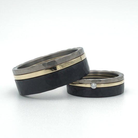 Set trouwringen met titanium, zwart zirkonium en 14kr geelgoud, hamerslagstructuur, damesring met diamant.
