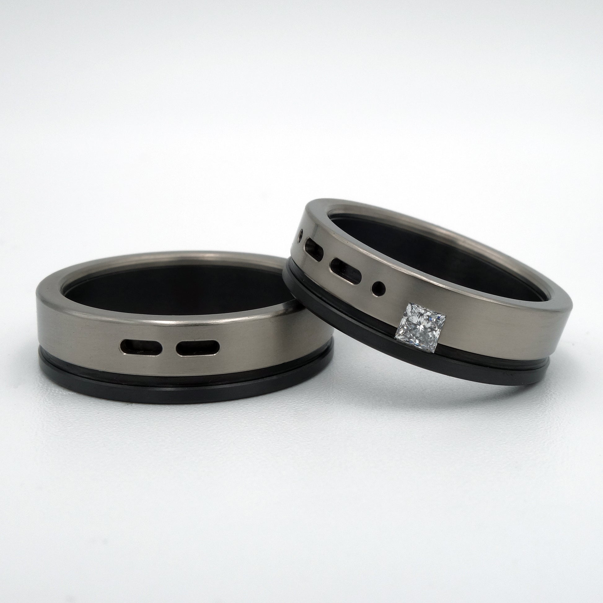 B&W Morse ringenset van titanium en zirkonium – moderne set met grafisch lijnenspel en prinsesgeslepen diamant in de damesring.


