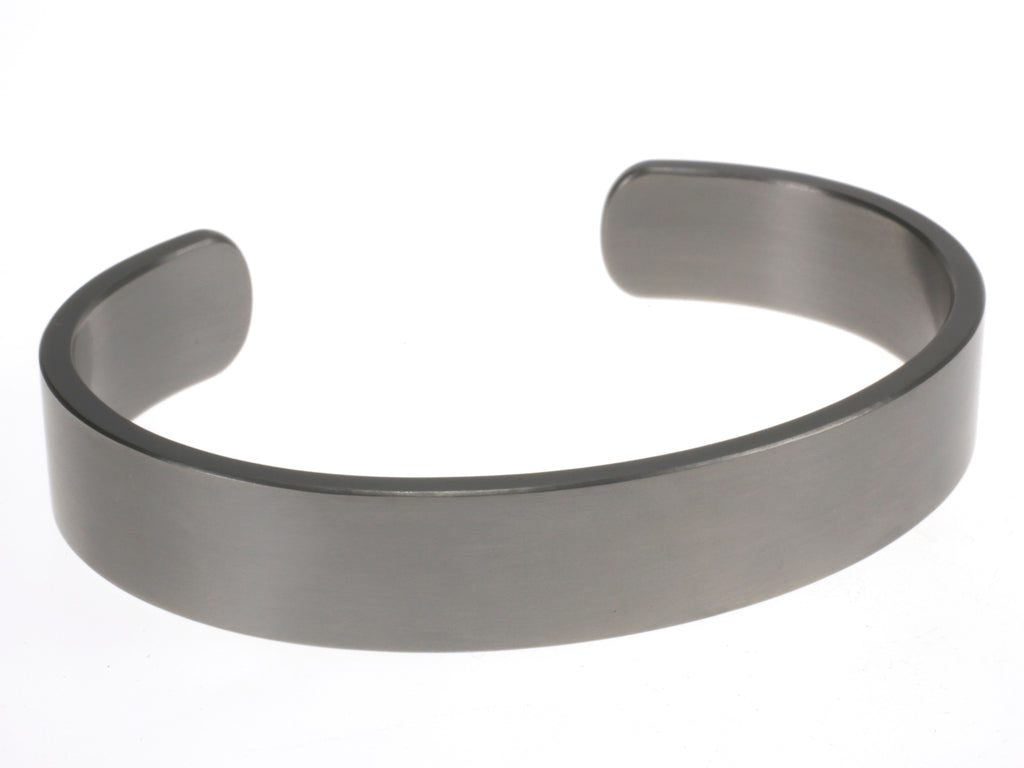 Brede matte titanium armband in open design, liggend op een witte achtergrond.