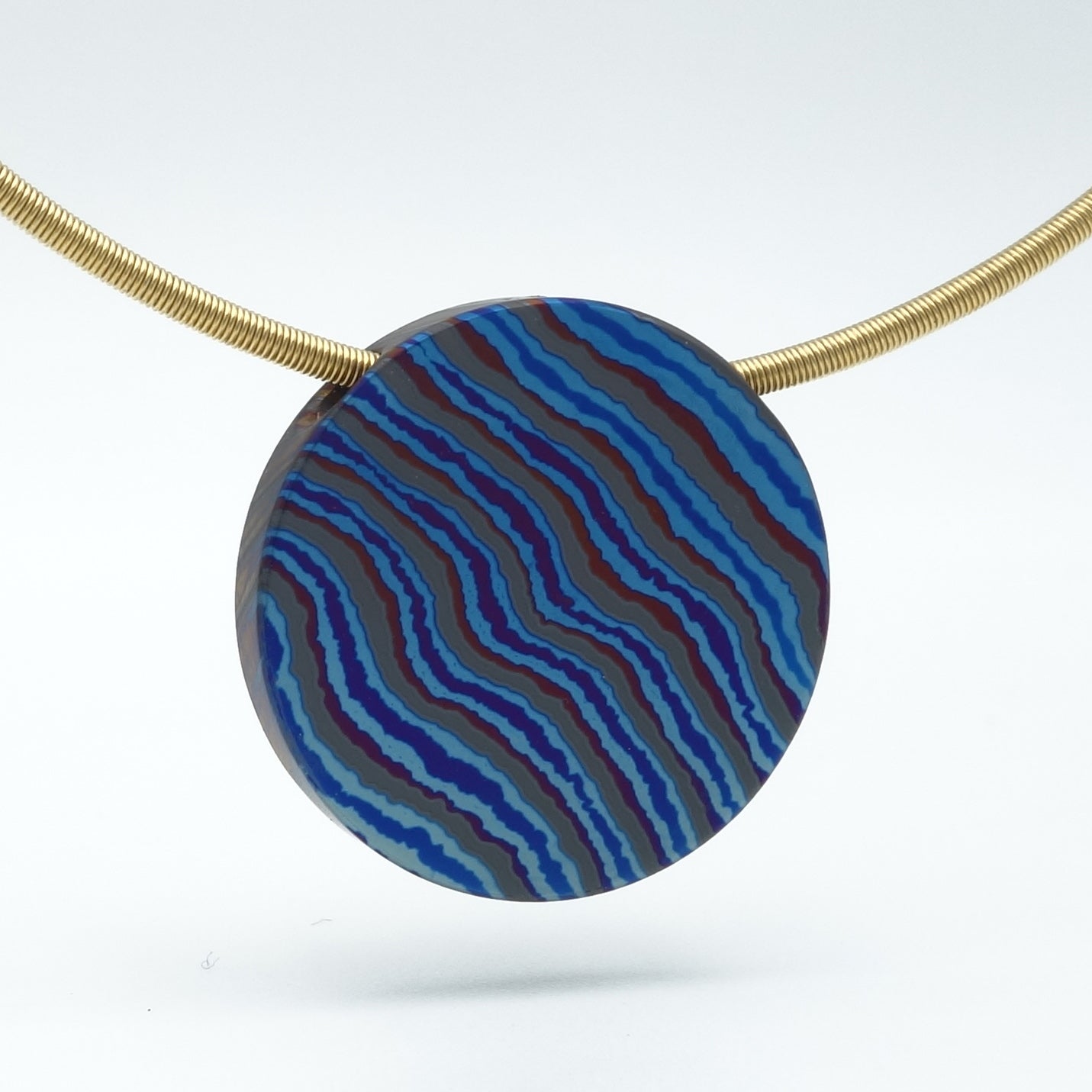 Hanger van zwart zirkonium met blauw titanium in een damast patroon.