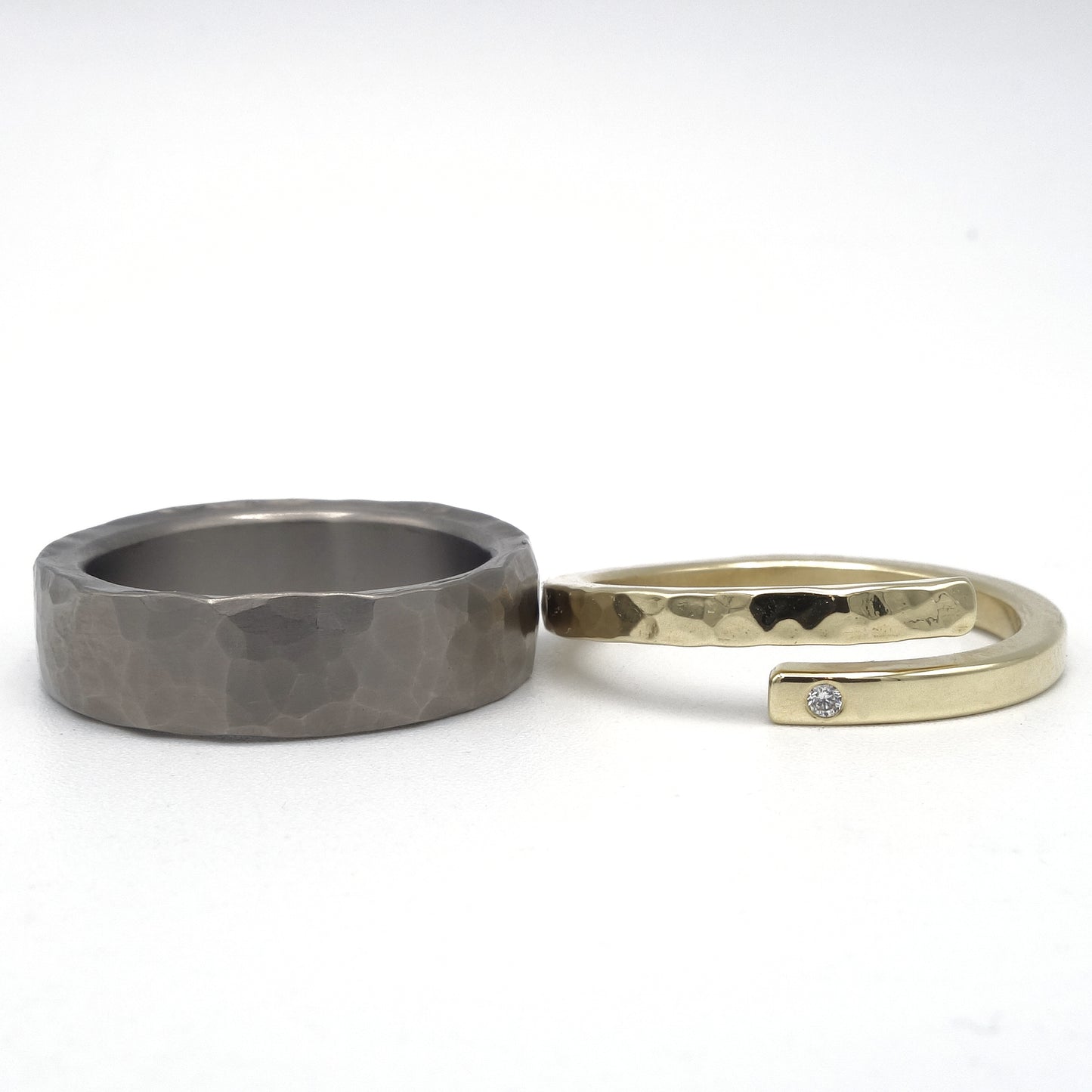 Stoere titanium ring met hamerslagstructuur en verfijnde geelgouden damesring met diamant van 0,01 ct en deels hamerslag.