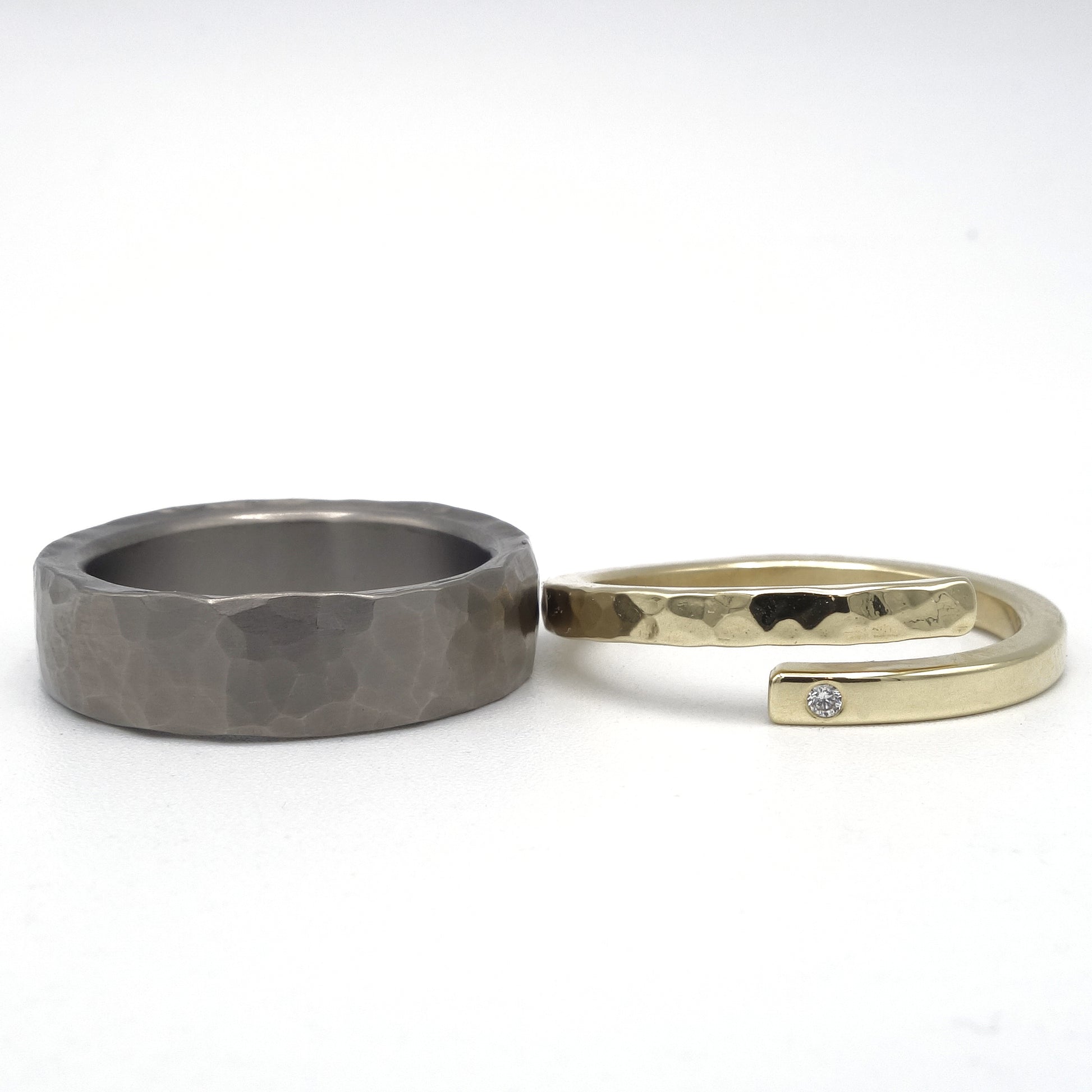 Stoere titanium ring met hamerslagstructuur en verfijnde geelgouden damesring met diamant van 0,01 ct en deels hamerslag.