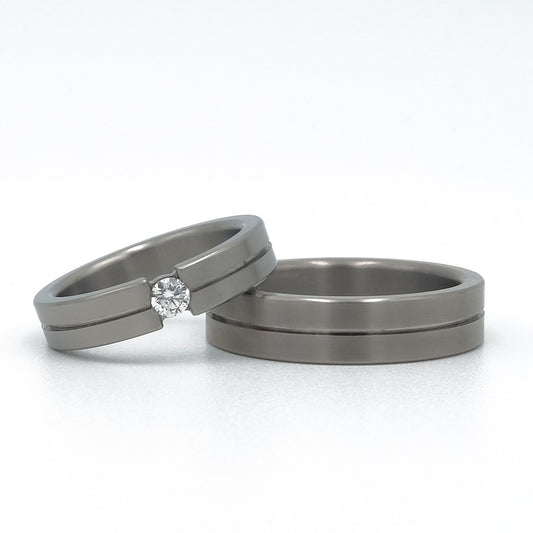 Titanium trouwringen Grey Stripe met grijze lijn en damesring met 0.10ct diamant in optische spanzetting.