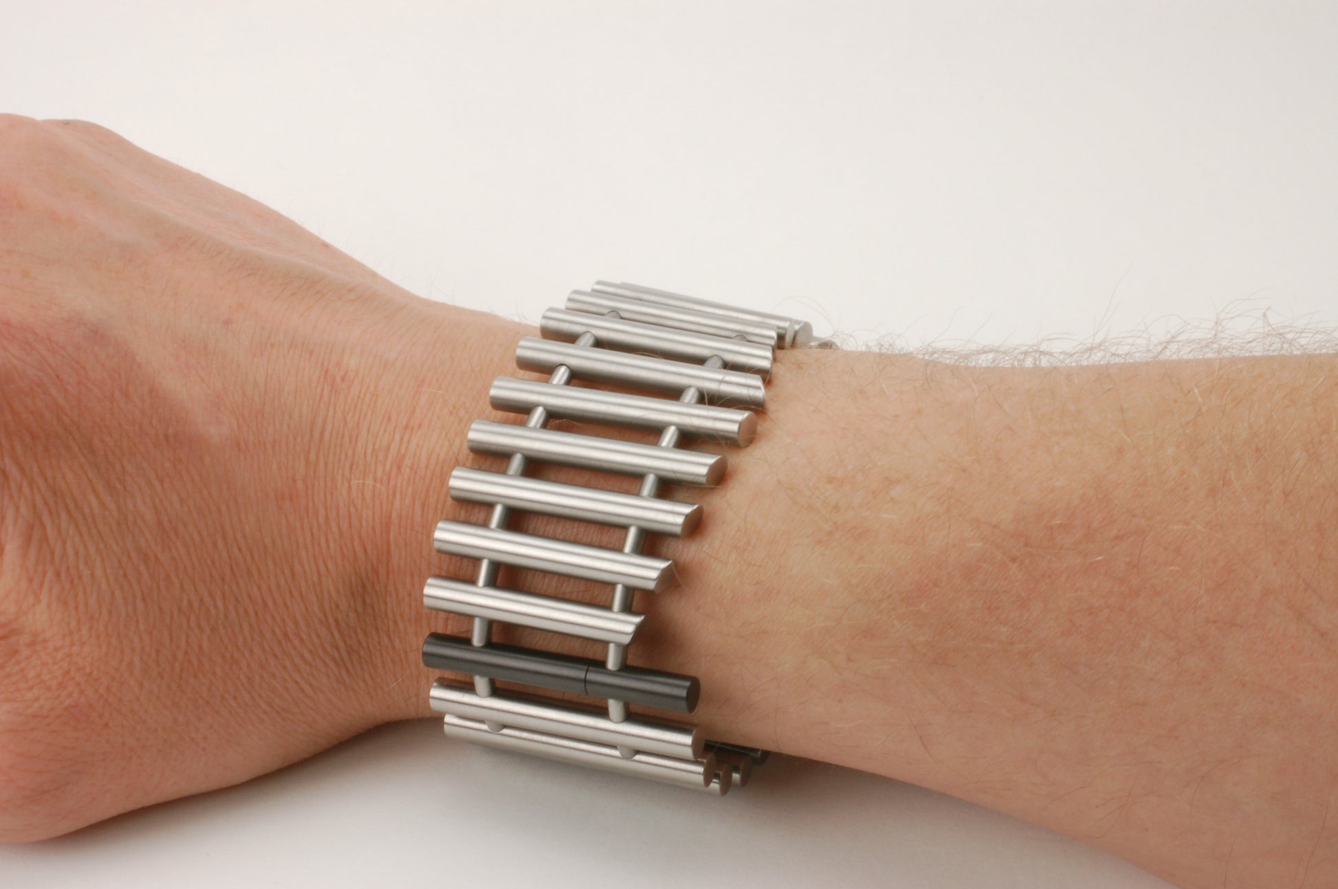 Titanium armband met verticale staven en één zwart zirkonium element, modern technisch ontwerp uit het atelier van Metal Art

Om pols