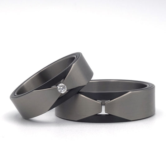 Set trouwringen van titanium en zirkonium met geometrische V-vorm en briljant geslepen diamant.