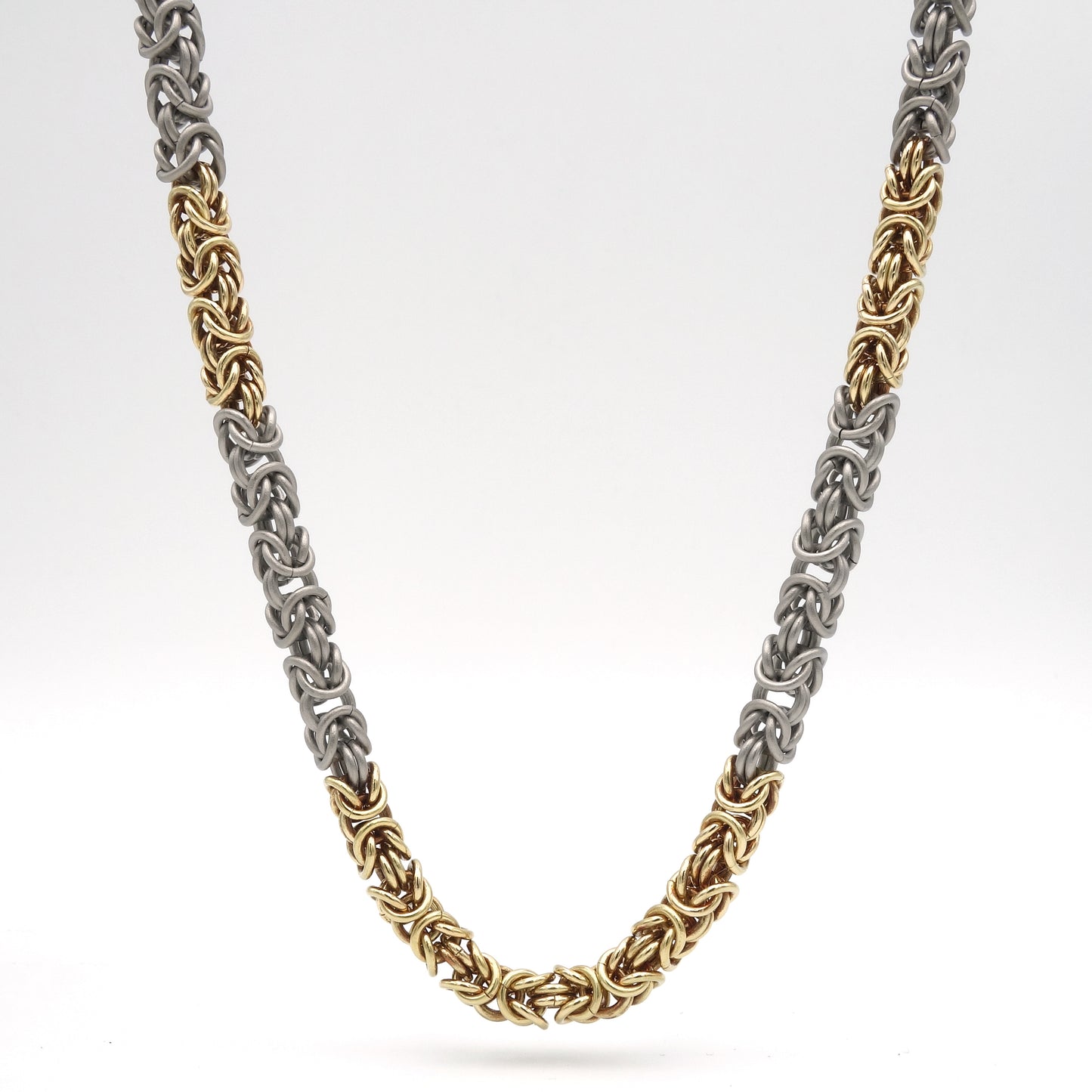 Handgemaakt collier met koningsketting schakels van titanium en 18 karaats geelgoud. 5.5 mm in dikte. Lengte 53 cm.