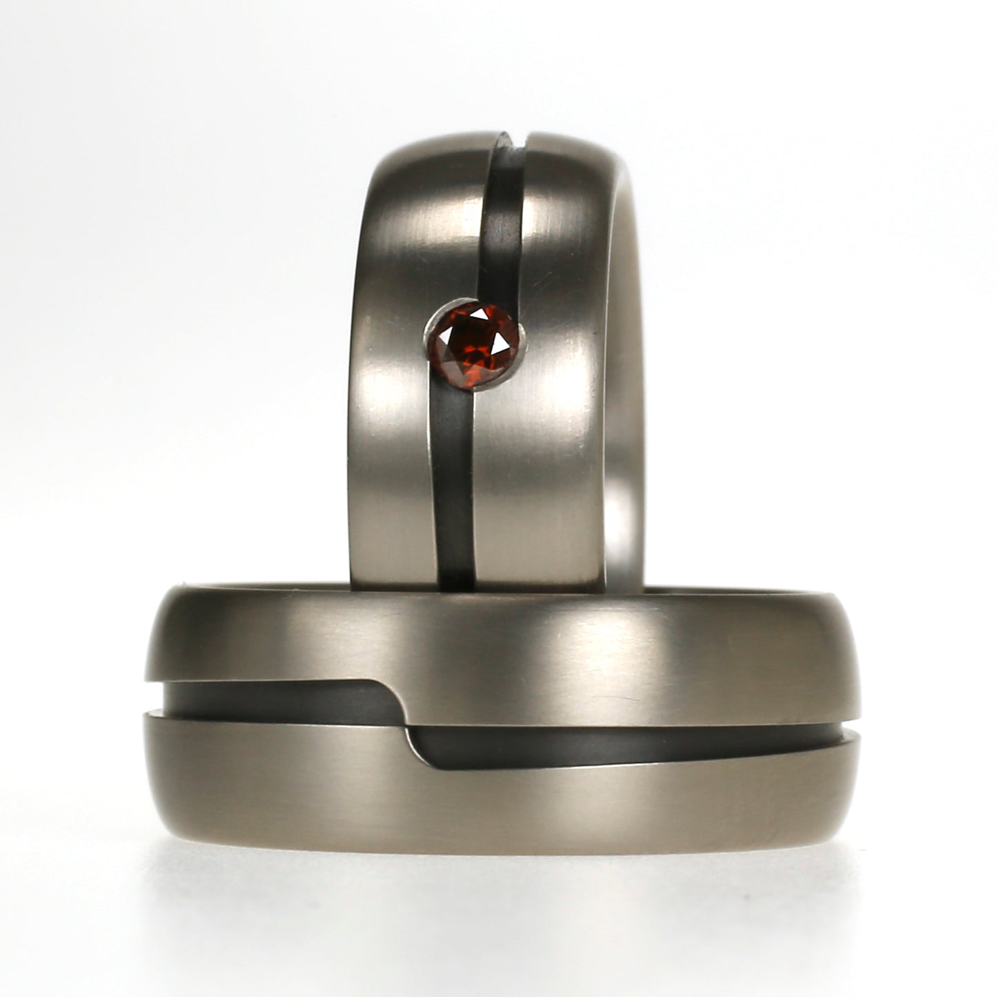 Titanium trouwringen met zwarte zirkonium inleg en rode diamant, uniek lijnenspel