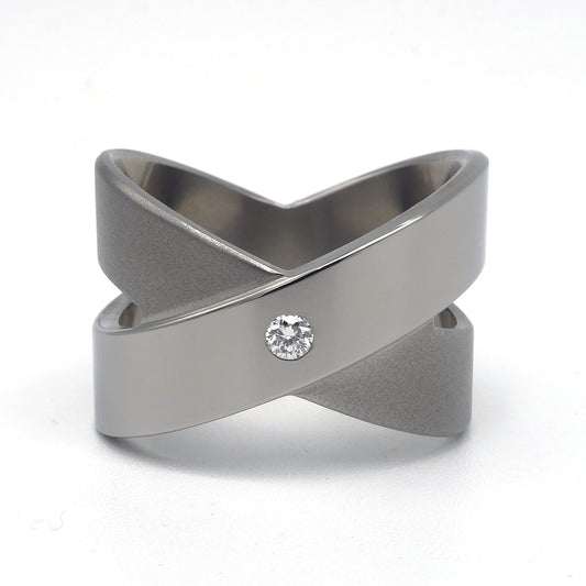 Brede titanium ring in open kruisvorm met gepolijste diagonale band en ingezette witte briljant 0,05ct, Lea II Smal van Metal Art Sieraden.