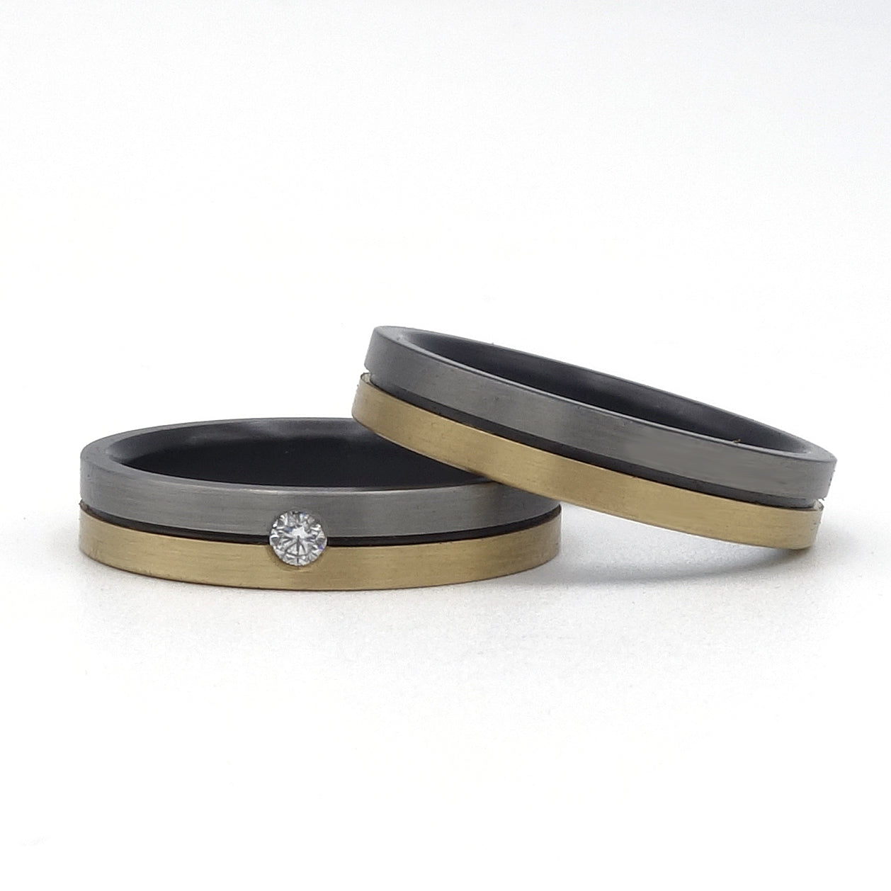 Lines ringenset van zirkonium en geelgoud – strak vormgegeven set met moderne lijnen en subtiele diamant in de damesring.

